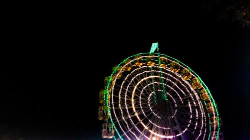 Illuminated ferris wheel against sky at night