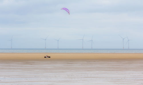 Distant view of person riding vehicle at beach