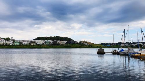 Sailboats moored in river against sky