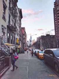 Woman on road in city against sky