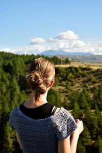 Rear view of woman looking at mountains against sky