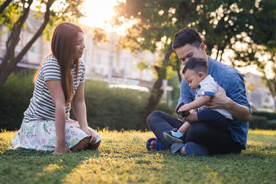 Family sitting on grass in park during sunset