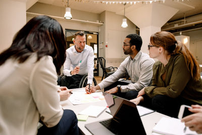 Serious colleagues looking at disabled manager while working in office