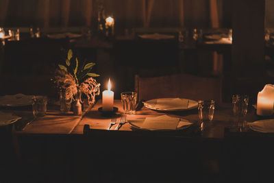 Illuminated candles on dining table in darkroom