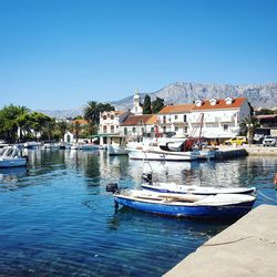 Boats moored at harbor against clear blue sky