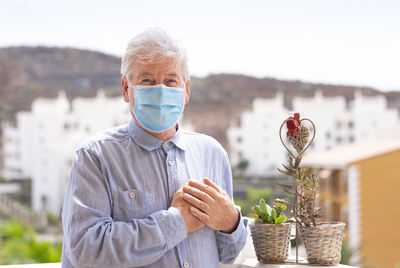 Portrait of senior man wearing mask standing outdoors