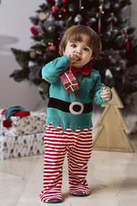 A little 12-month-old christmas elf with a christmas tree and gifts