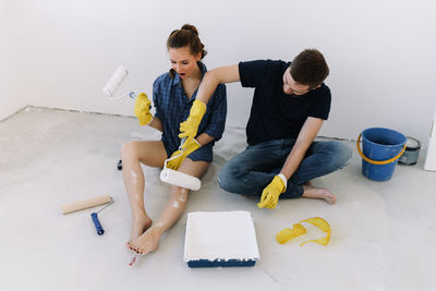 A young couple in love have moved into a new house and are making repairs painting white walls