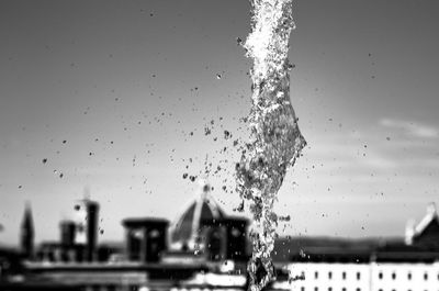 Water drops on glass window against buildings