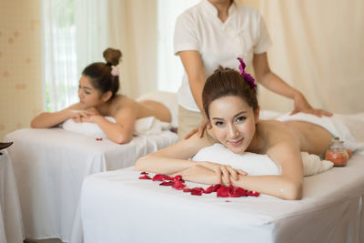 Midsection of masseur massaging young woman on table in spa