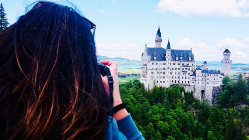 Rear view of woman looking at buildings against sky