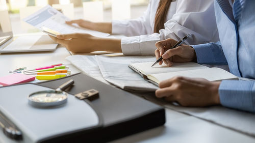 Midsection of man holding paper at table