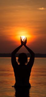 Silhouette person in sea against sky during sunset