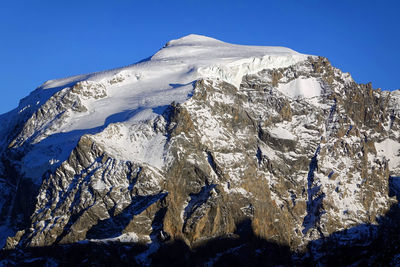 Scenic view of snowcapped mountains against clear blue sky