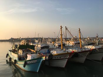 Boats moored at harbor against sky