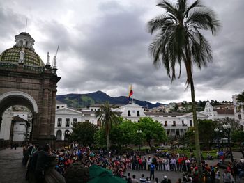 People at town square against cloudy sky