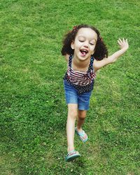 Portrait of happy girl playing on grassy field in park