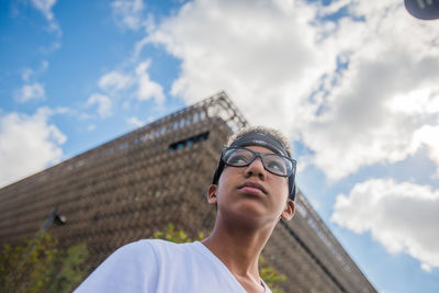 Low angle portrait of woman looking against sky