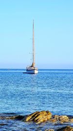 Sailboat sailing on sea against clear sky