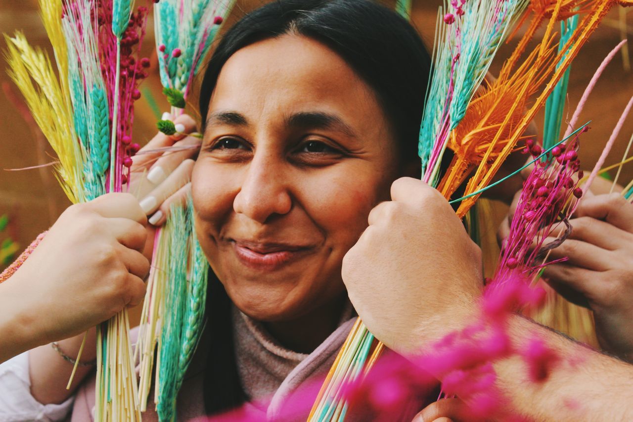 portrait, adult, headshot, one person, multi colored, smiling, women, holding, emotion, happiness, young adult, tradition, tribe, looking at camera, female, celebration, hand, paint, close-up, traditional clothing, festival, creativity, cheerful, lifestyles, human face, occupation, front view, arts culture and entertainment, working