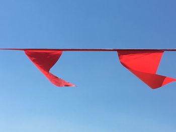 Low angle view of flags against clear blue sky