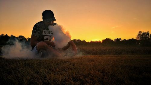 Man standing on field against sky during sunset