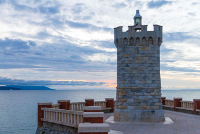 Lighthouse on building by sea against sky