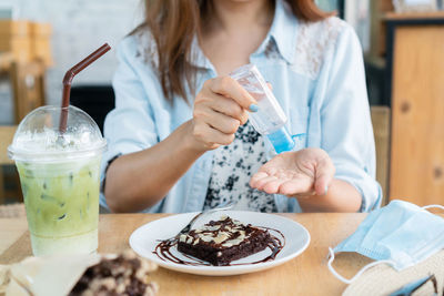 Midsection of woman holding hand sanitizer at cafe