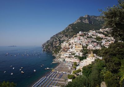 Townscape by sea against clear blue sky