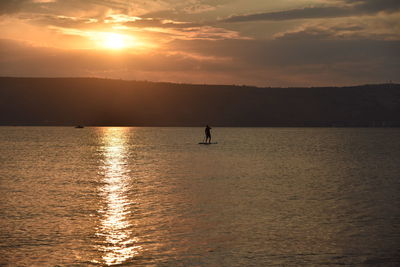 Man sail on a sup board in a large lake during sunrise. stand up paddle boarding - active 