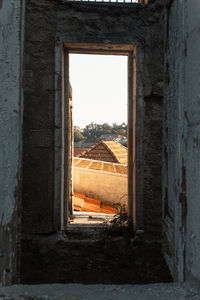Old building against clear sky seen through window