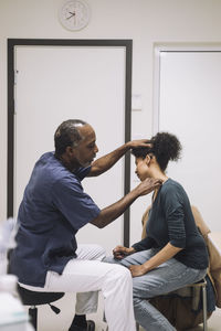 Side view of mature healthcare expert examining female patient in medical clinic
