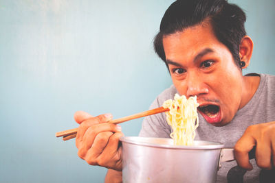 Man shouting while looking at noodles against wall at home