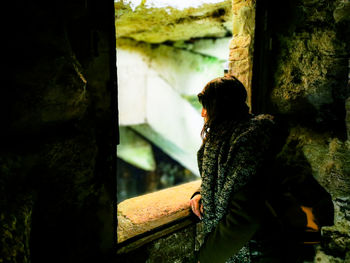 Woman looking through window from abandoned building