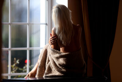 Rear view of woman looking through window