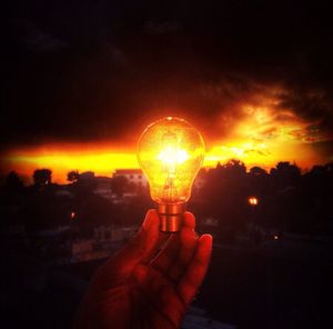 Cropped image of hand against sky during sunset