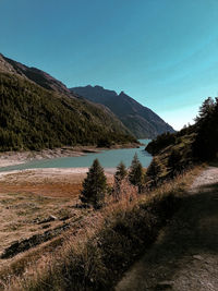 Scenic view of land and mountains against clear blue sky