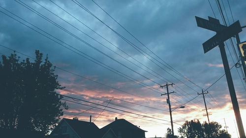 Low angle view of power lines against cloudy sky