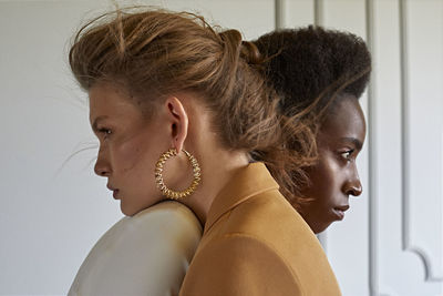 Side view of young women looking away while embracing