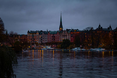 River amidst buildings against sky at dusk