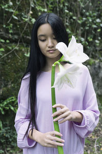 Asian teenage girl in purple blouse holding white flowers in her hands v