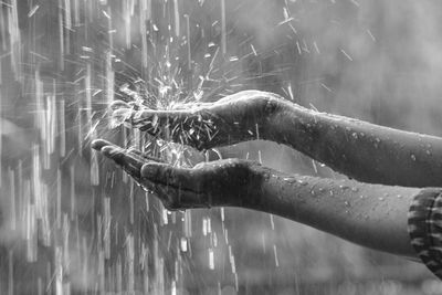 Close-up of hand holding leaf over water