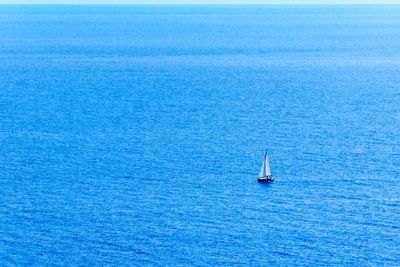 Sailboat sailing in sea against blue sky