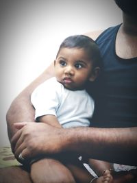 Close-up of father with baby sitting at home