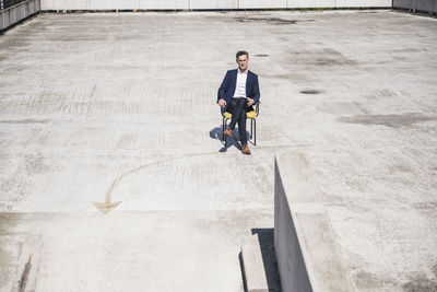 Mature businessman sitting with legs crossed at knee on building terrace