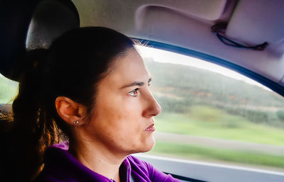 Close-up portrait of woman looking through car window