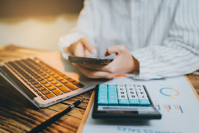 Midsection of man using calculator