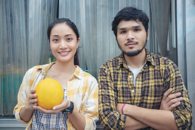 Portrait of smiling young woman holding lemon by man