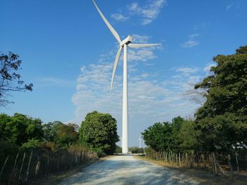 Low angle view of windmill and trees against sky