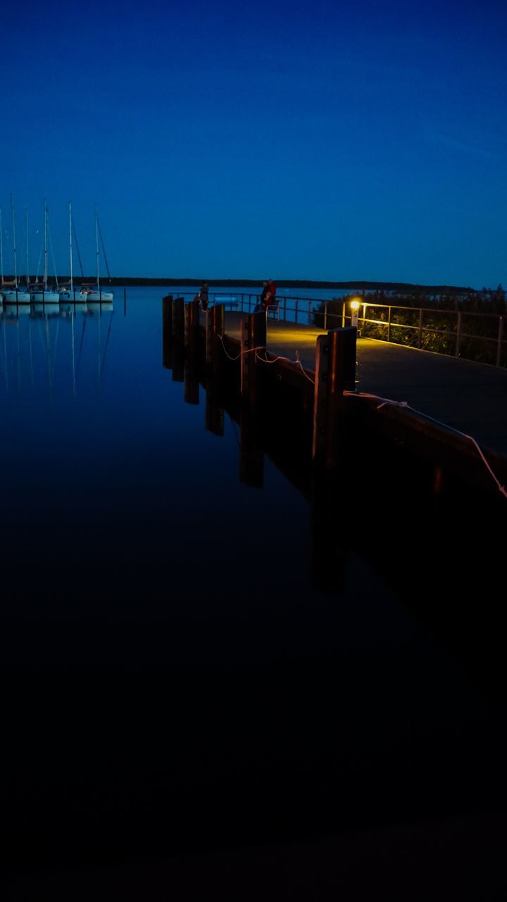 PIER OVER LAKE AGAINST CLEAR BLUE SKY AT NIGHT